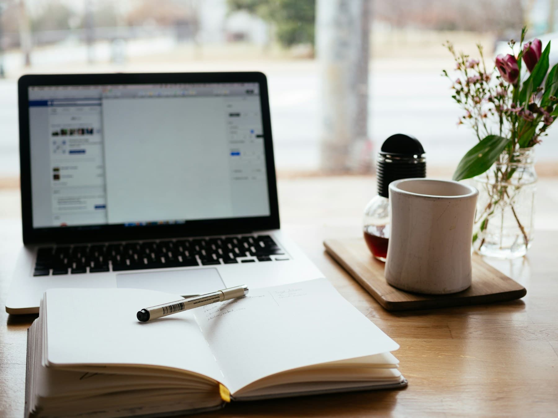 Laptop, notebook and mug on a bright desk